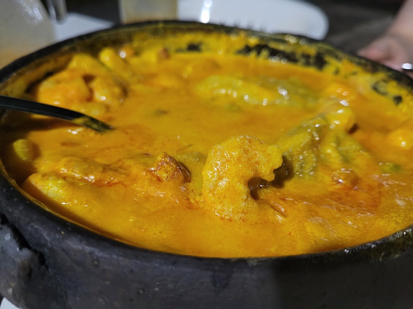 Moqueca de camarão de perto, no caldo dourado dentro do tacho de ferro