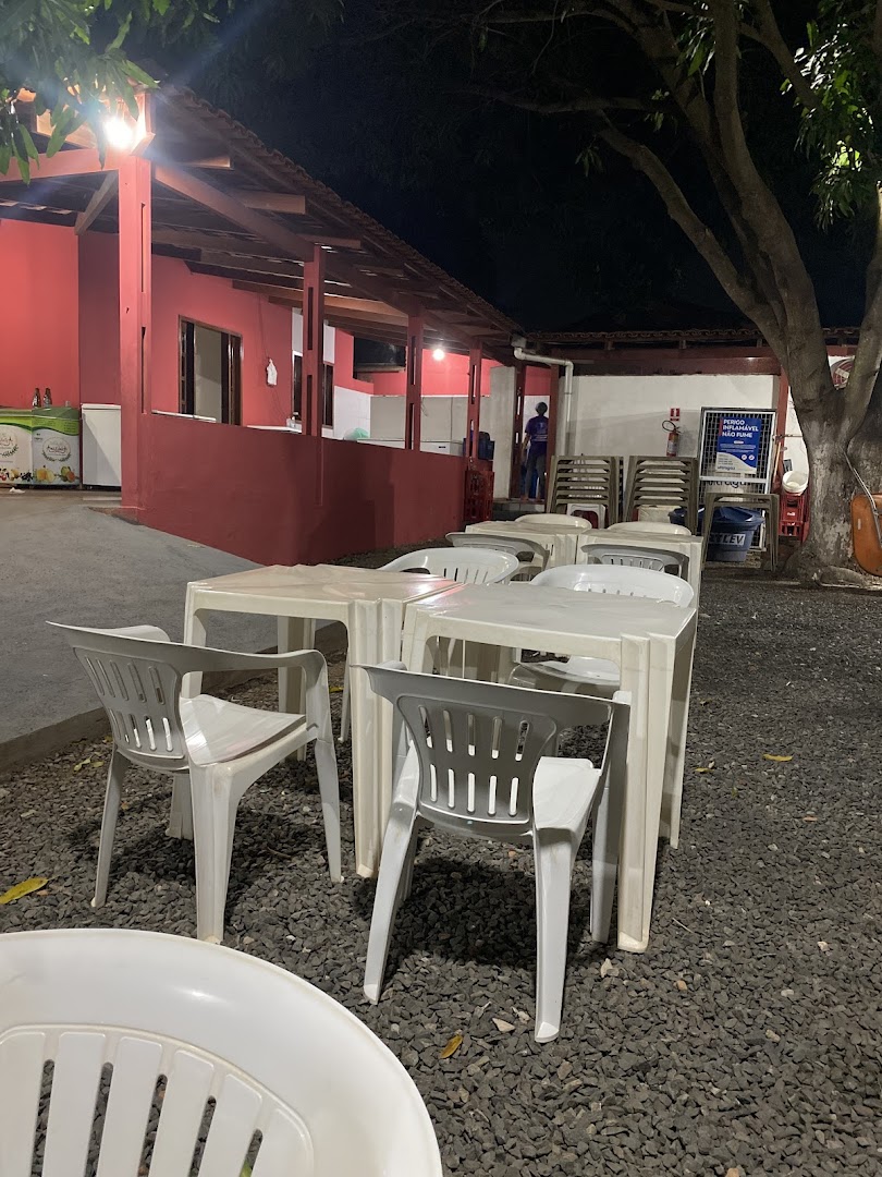 Ambiente à noite com mesas e a fachada vermelha iluminada