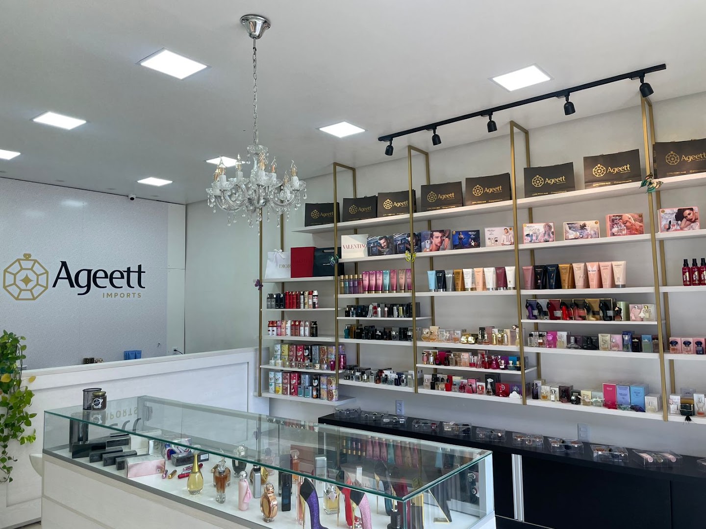 Interior elegante da loja Ageett com lustre e vitrines de perfumes