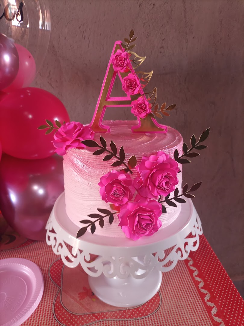Bolo rosa buttercream com rosas pink e inicial dourada, cercado de balões