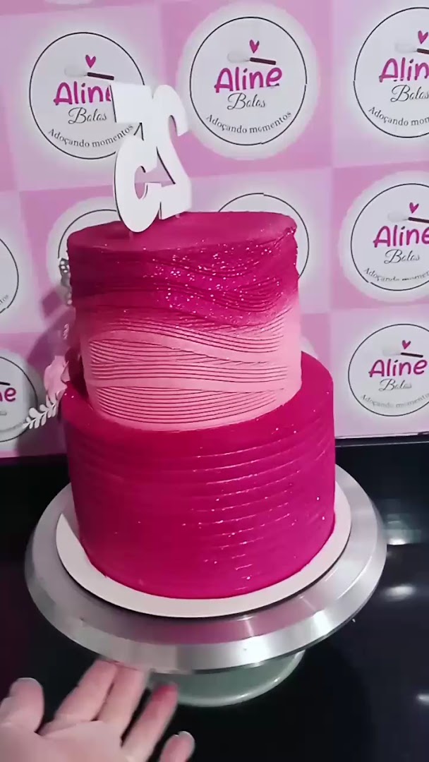 Bolo de dois andares em degradê rosa e magenta com topo prateado, num pedestal de bolo