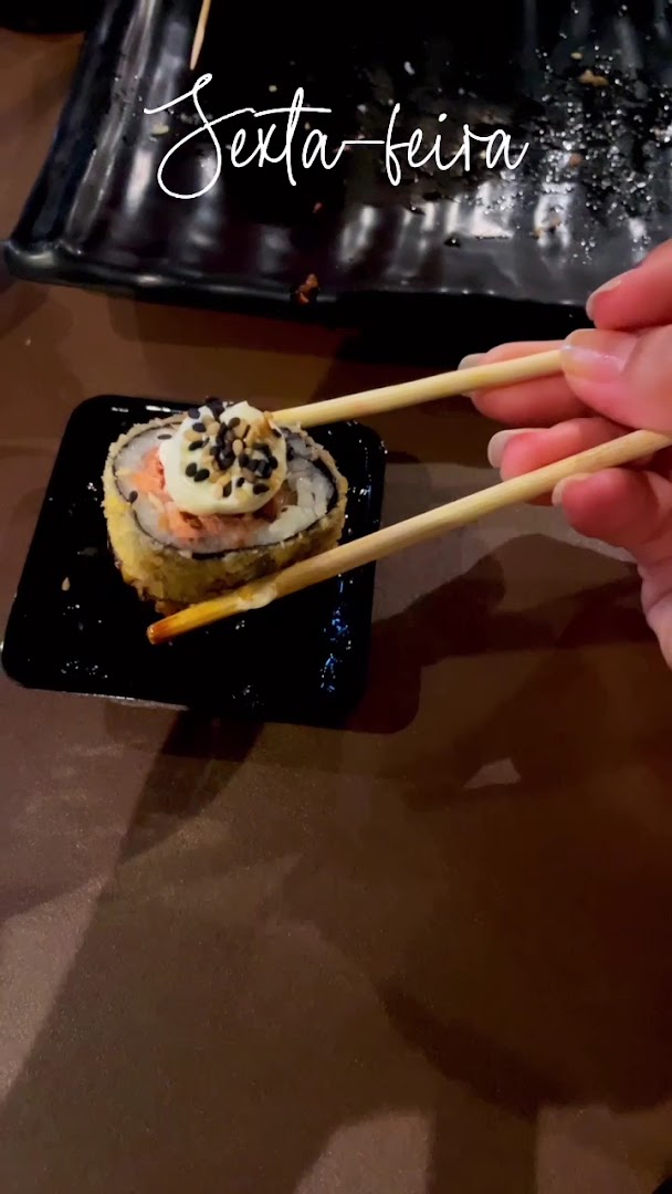 Rolinho de sushi sendo pego com o hashi