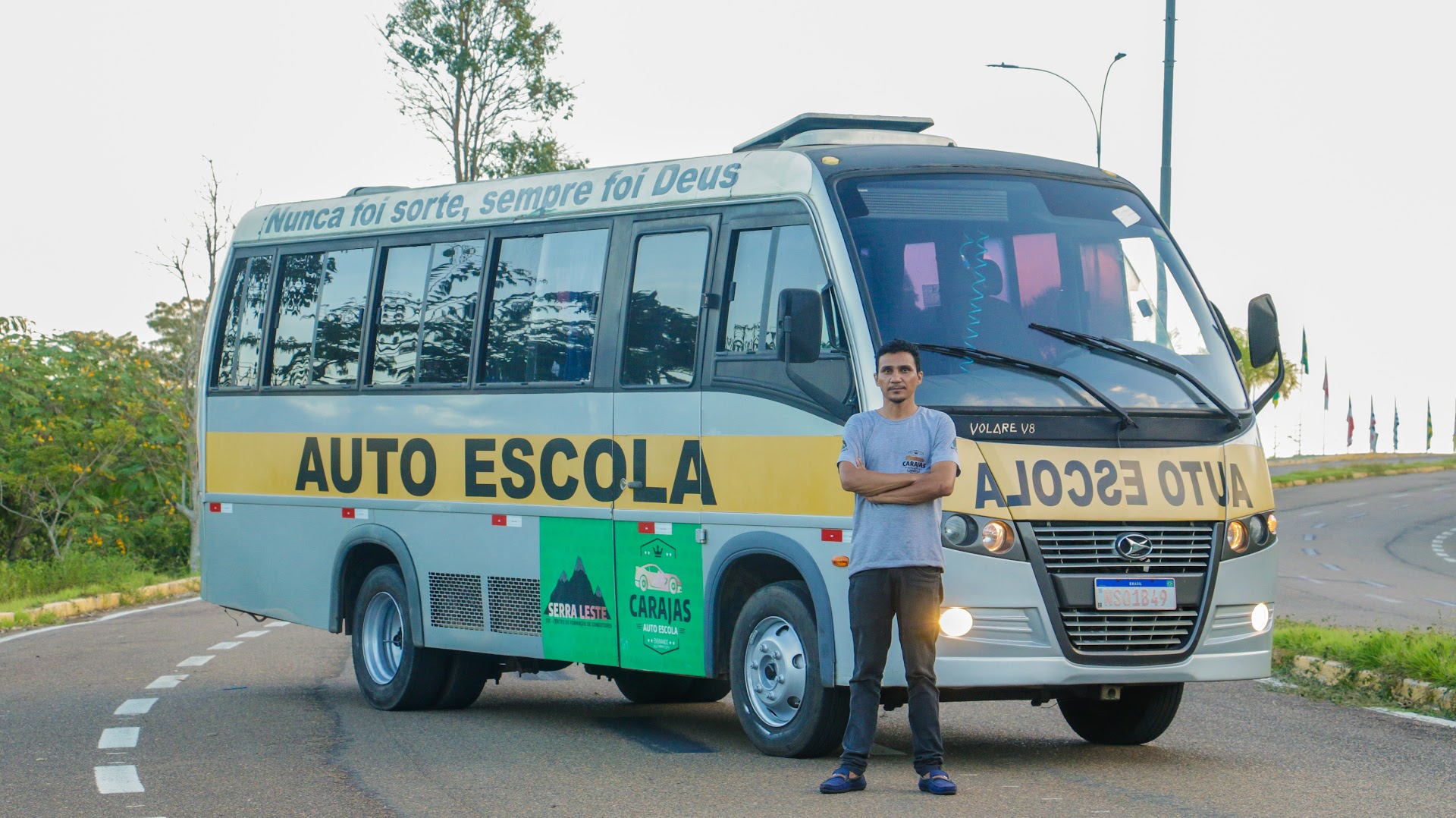 Micro-ônibus prata e amarelo da Auto Escola Carajás com instrutor na frente