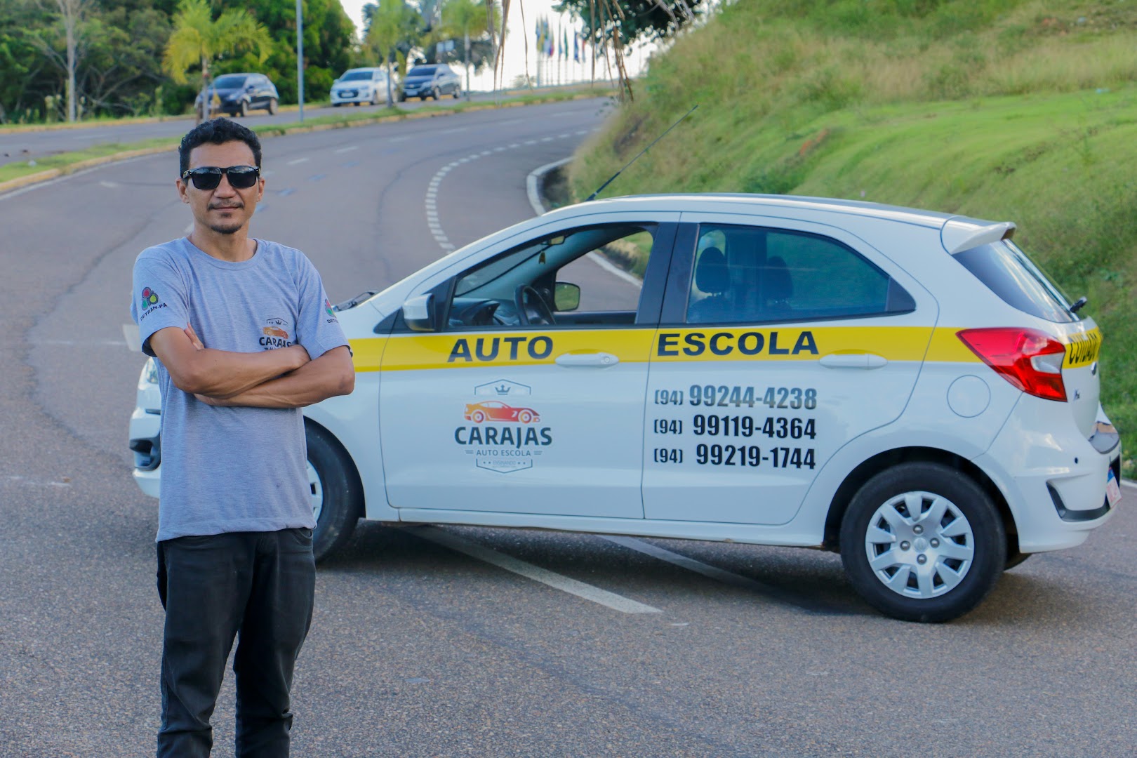 Carro branco plotado da Auto Escola Carajás com instrutor ao lado