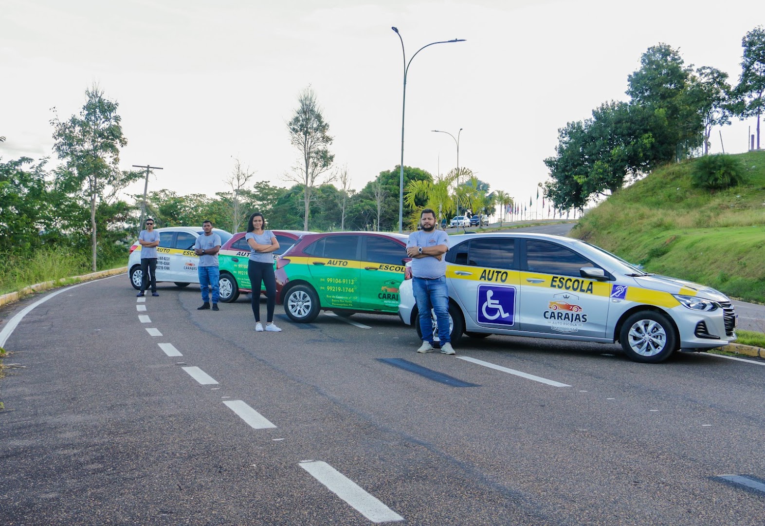 Frota de carros da Auto Escola Carajás enfileirada na rua com a equipe