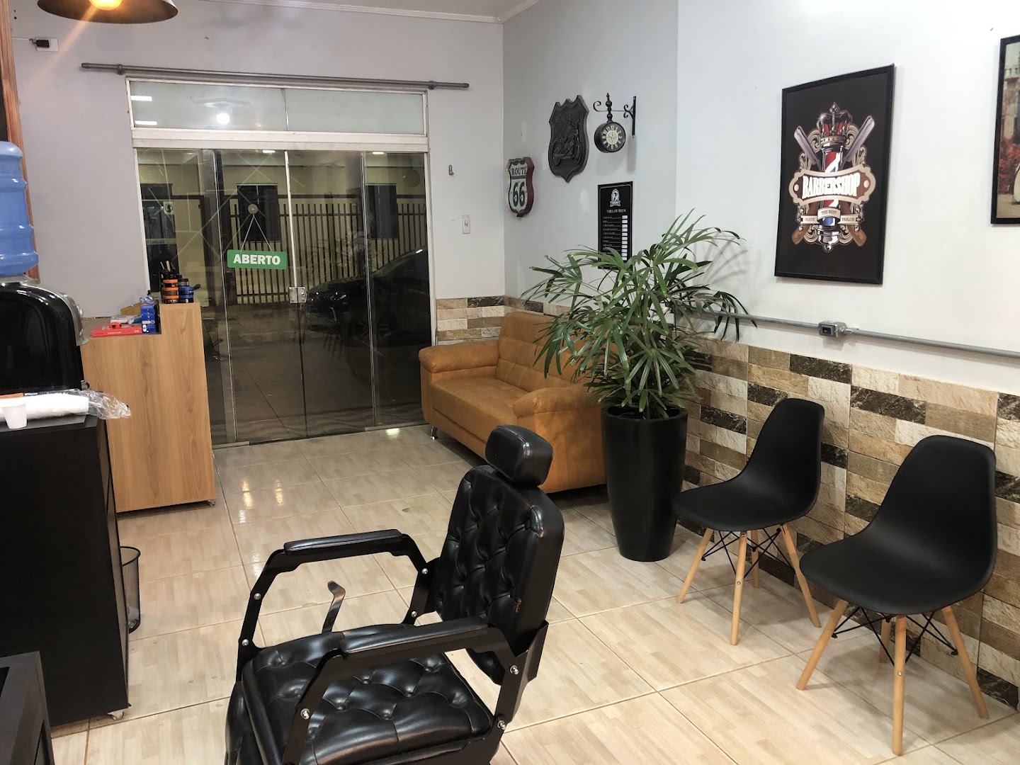 Recepcao da Barbearia Club com sofa de couro caramelo, planta e parede de pedra