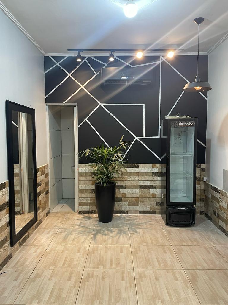 Interior da Barbearia Club com parede geometrica preta, planta e frigobar