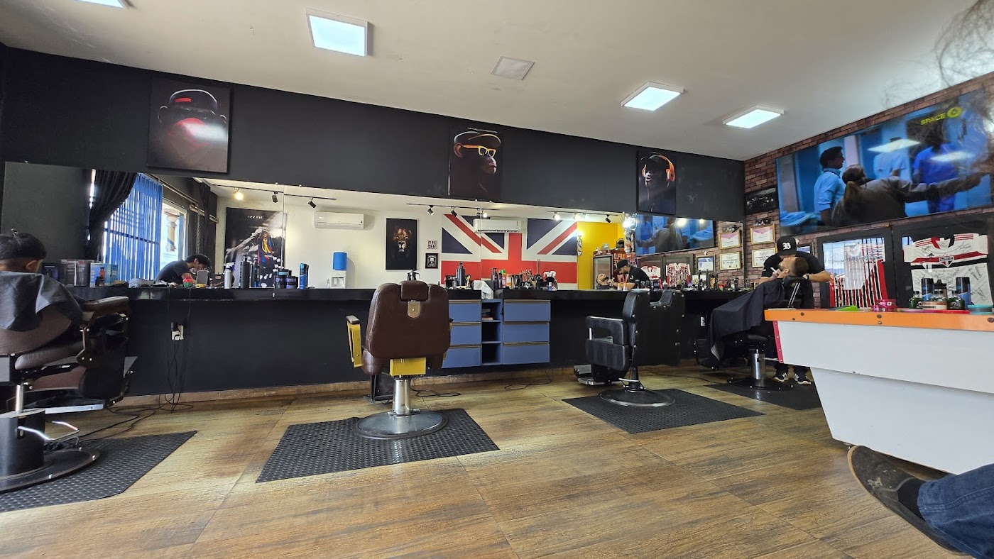 Interior da Paulista Barber Shop com cadeiras de barbeiro, piso de madeira e arte urbana nas paredes