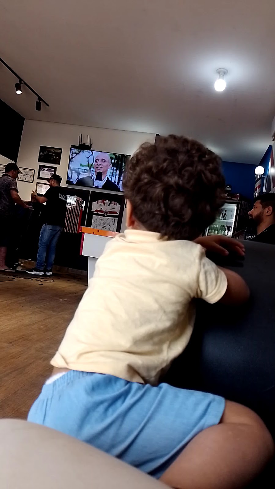 Cliente esperando no salão da Paulista Barber Shop com televisão e ambiente familiar