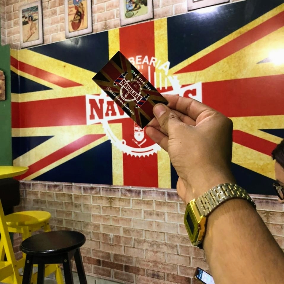 Parede da barbearia com bandeira britânica e o cartão da Barbearia Navalhas com caveira e navalhas cruzadas