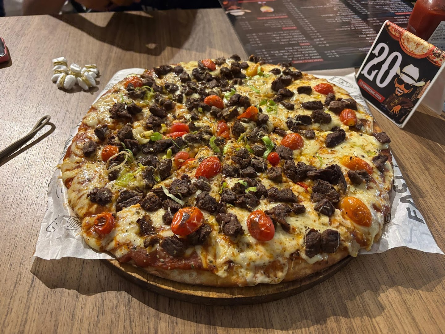 Pizza coberta de carne suculenta, queijo e tomatinhos