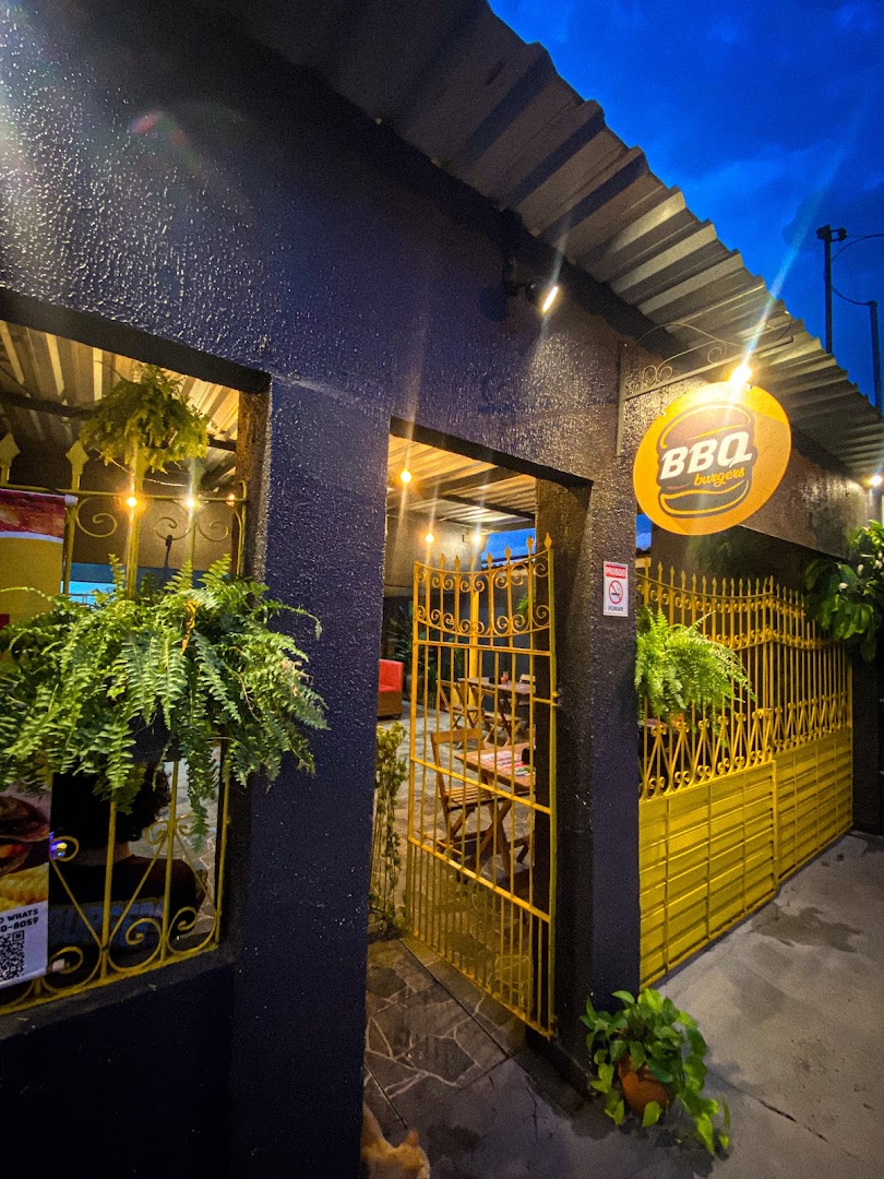Fachada preta e amarela da BBQ Burgers à noite com o logo iluminado