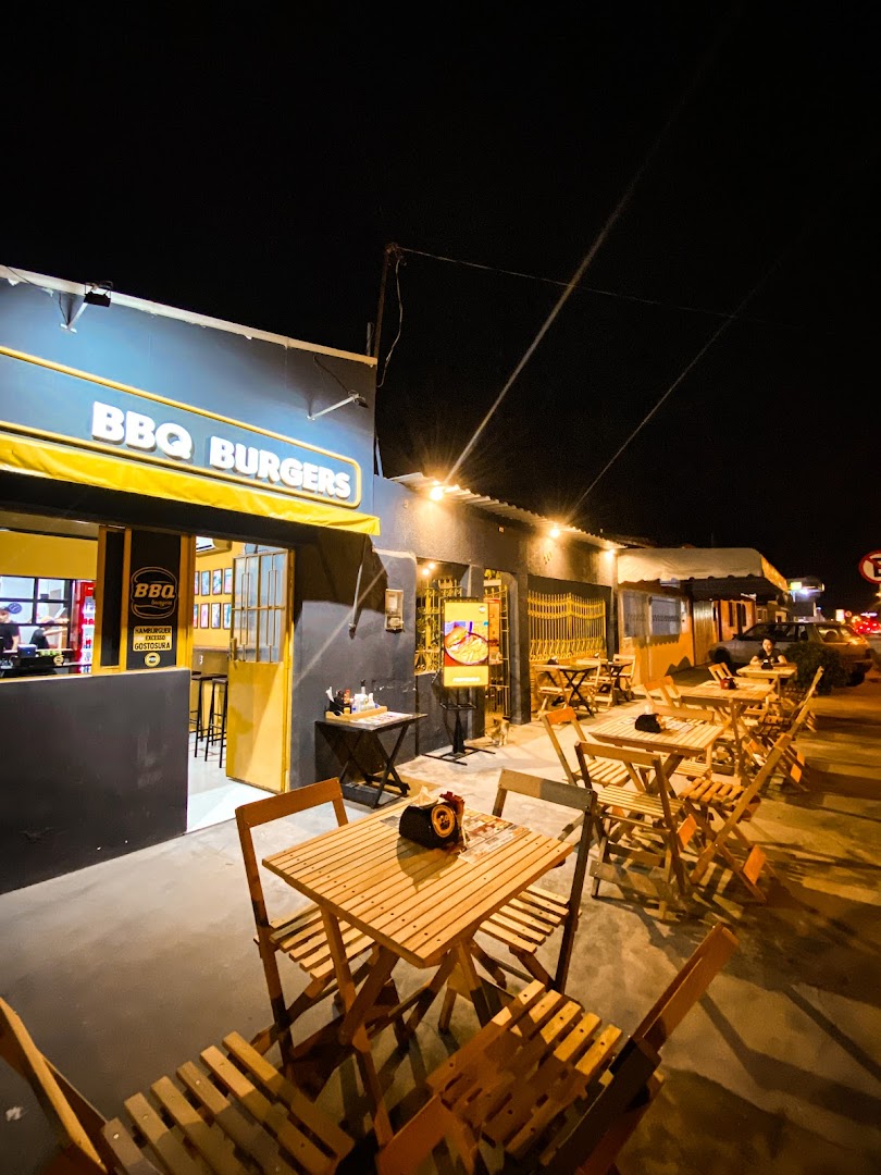 Fachada da BBQ Burgers à noite com área de mesas iluminada