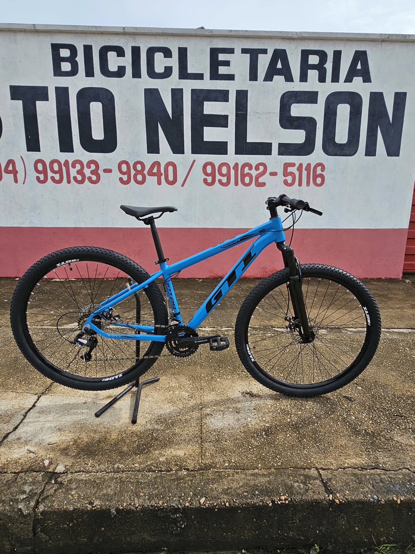 Mountain bike azul aro 29 fotografada no muro da loja