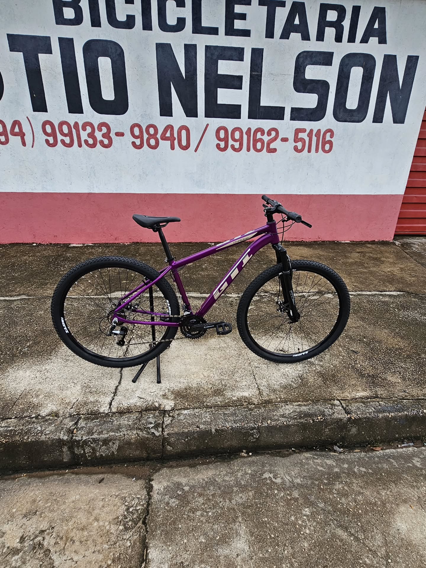 Mountain bike roxa aro 29 fotografada no muro da loja