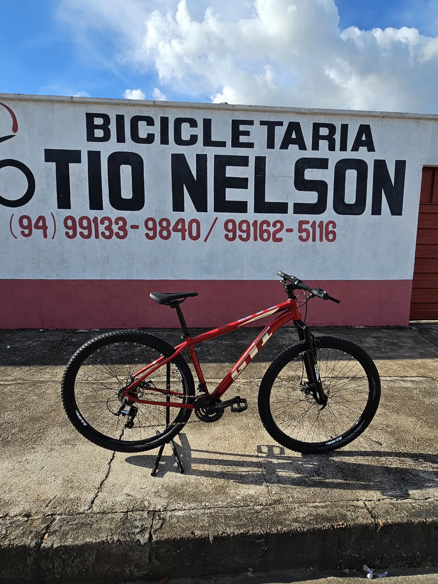 Mountain bike vermelha aro 29 na frente do muro pintado à mão da Bicicletaria Tio Nelson