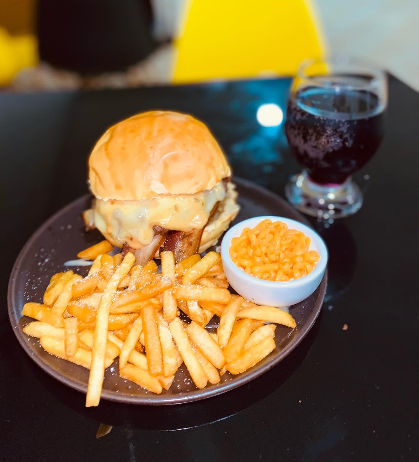 Hambúrguer com bacon e queijo derretido, batata frita e refrigerante no prato
