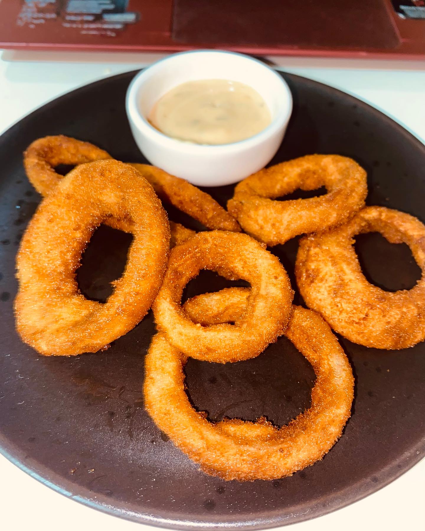 Porção de onion rings crocantes com molho para acompanhar