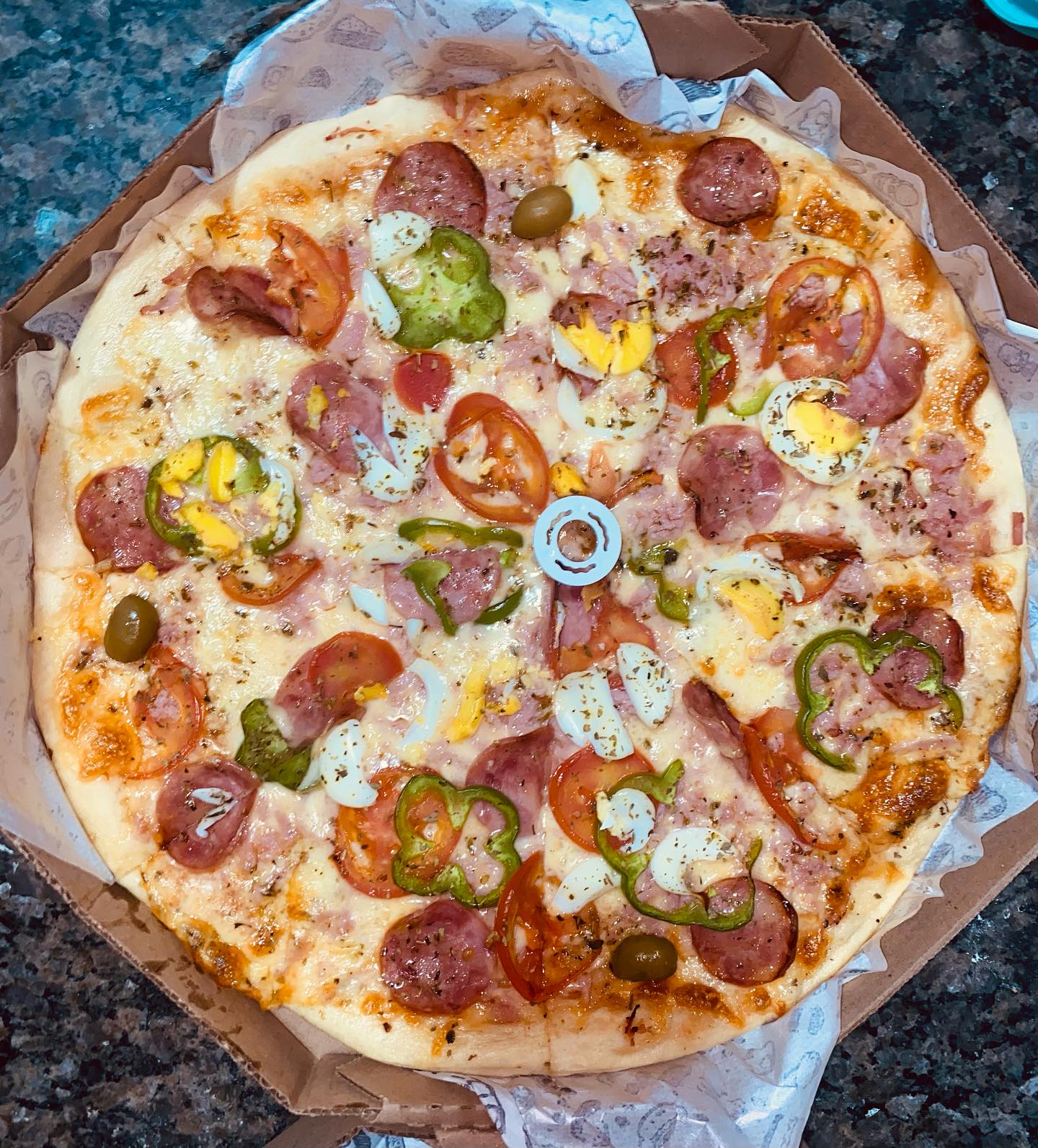 Pizza grande da Brittus com calabresa, presunto, ovo, tomate e pimentão na caixa