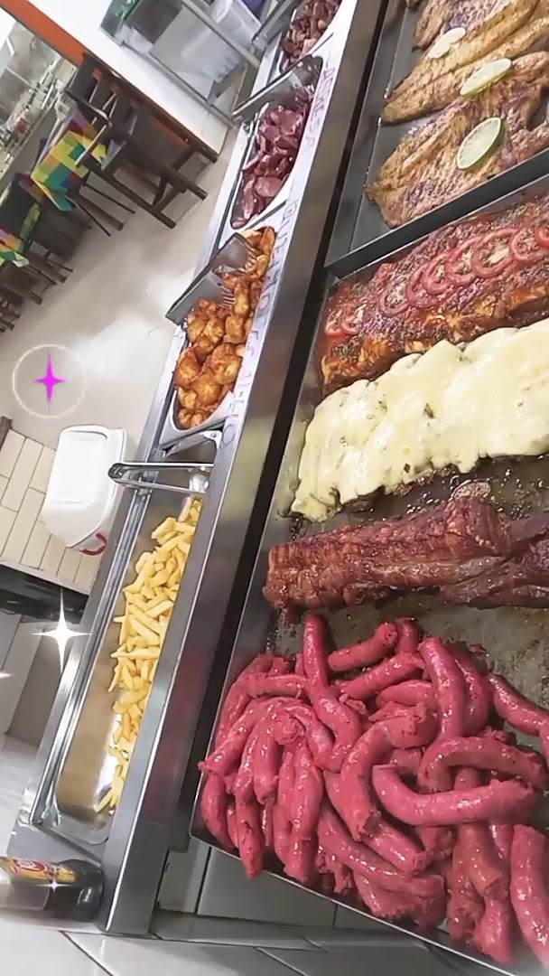 Churrasco na brasa com linguiça, espetos e carnes variadas no balcão da Churrascaria Quero Mais