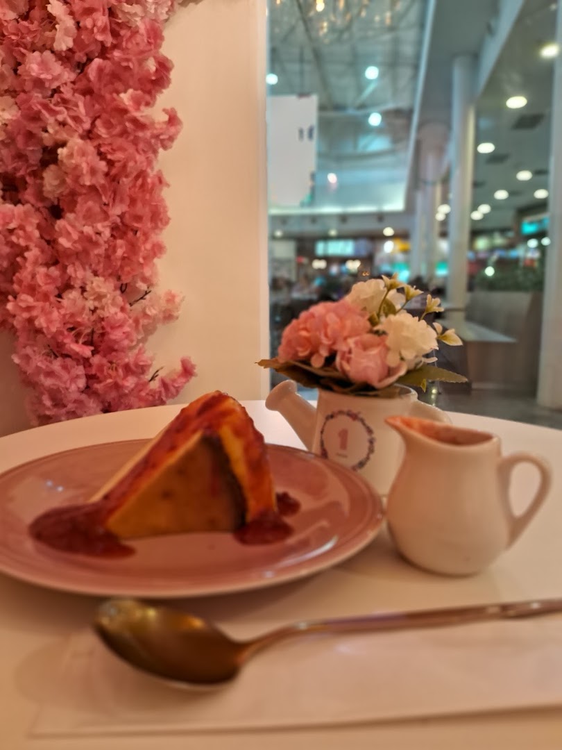 Fatia de cheesecake com calda e flores de cerejeira, ao lado de um café