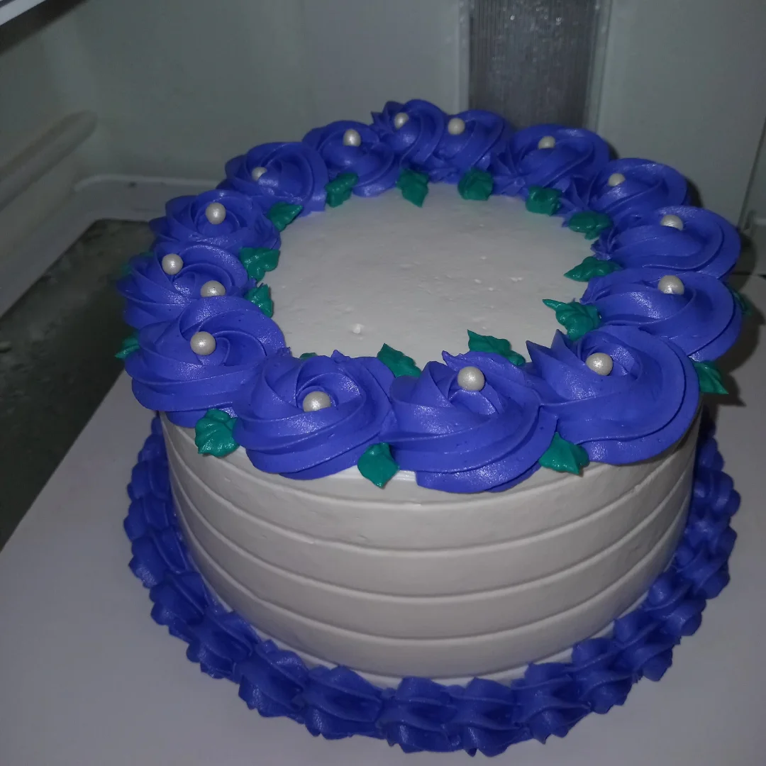 Bolo branco com coroa de rosas em azul e pérolas