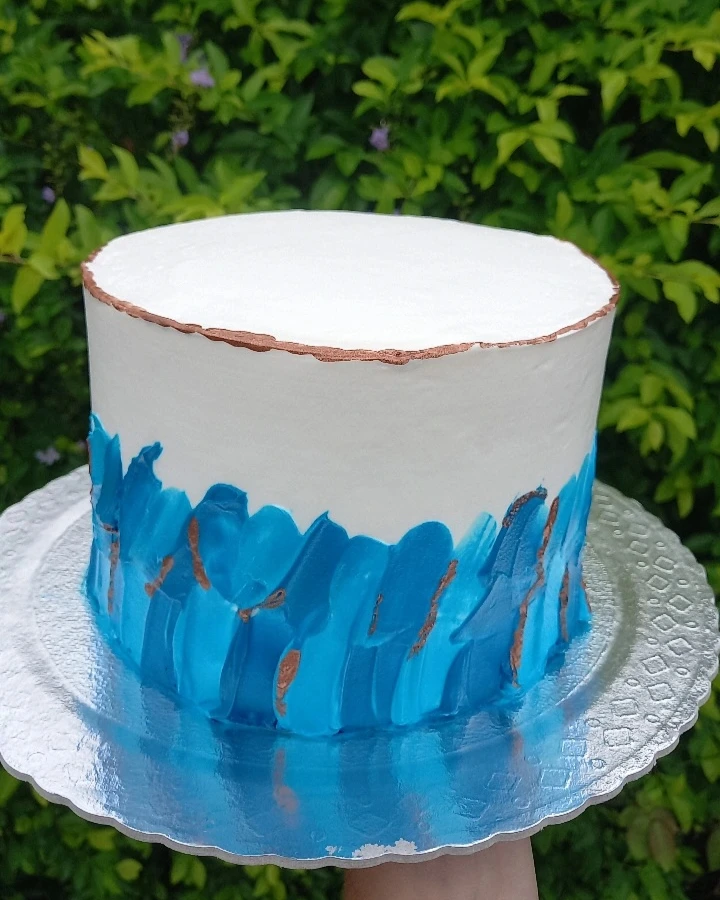 Bolo branco com pinceladas azuis e borda em cobre
