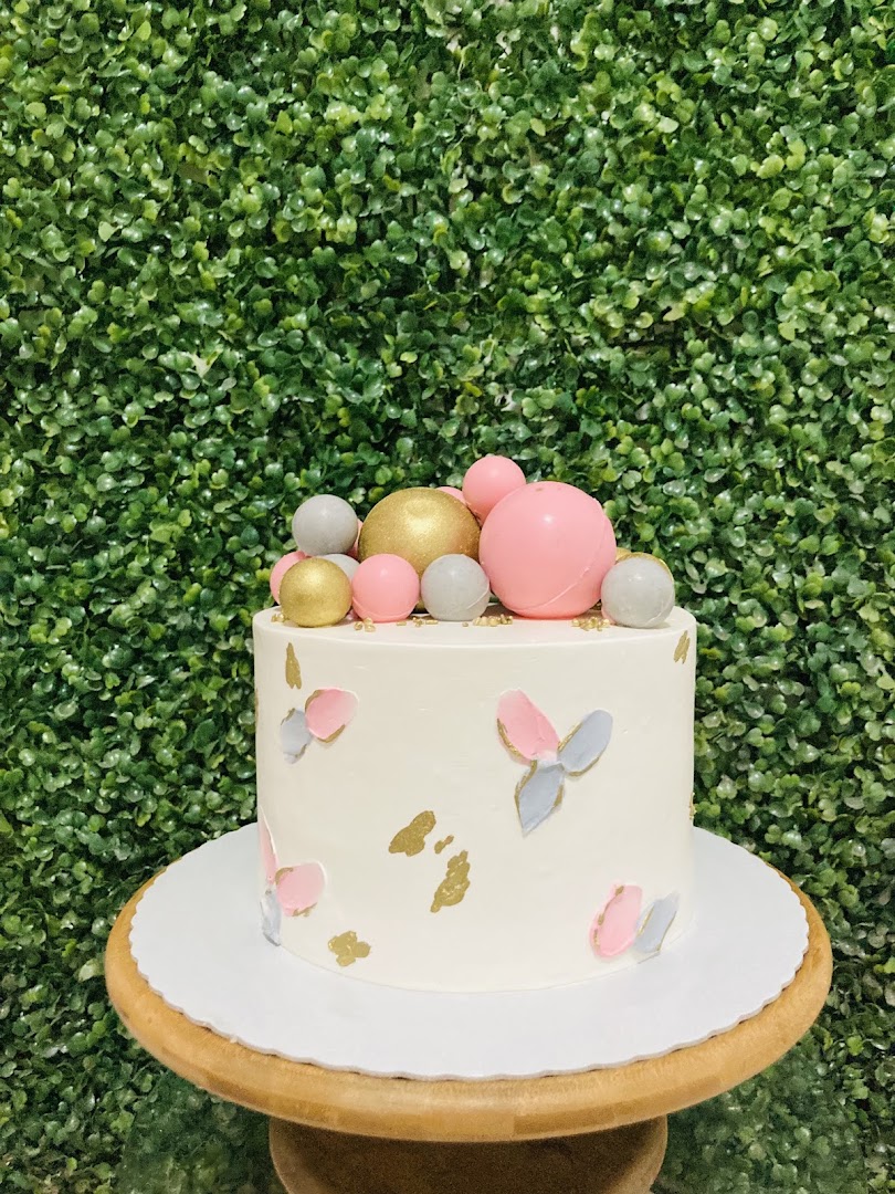 Bolo branco decorado com esferas e detalhes em tons pastel