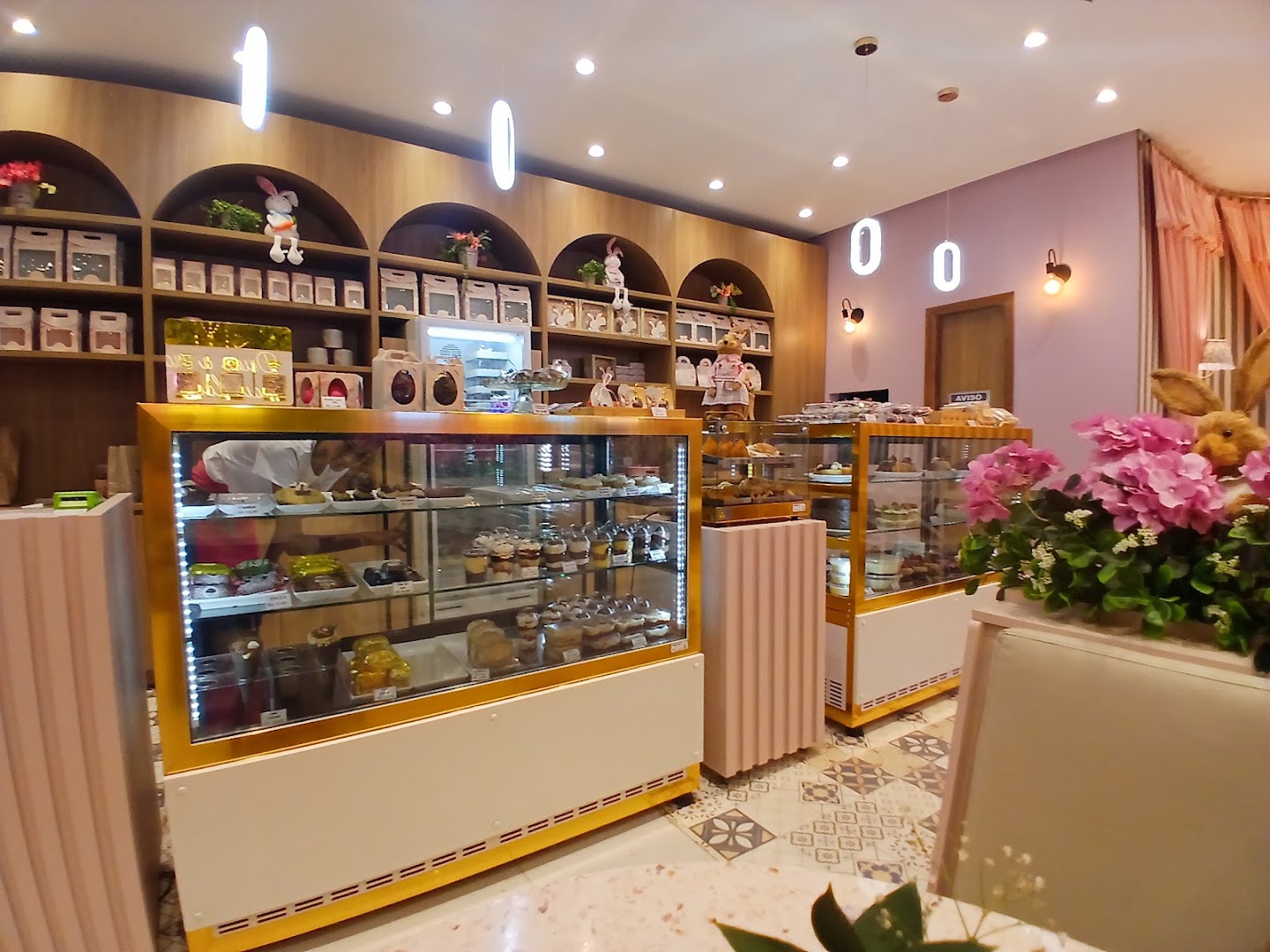 Interior da loja com vitrines em arco, prateleiras de madeira e lustre