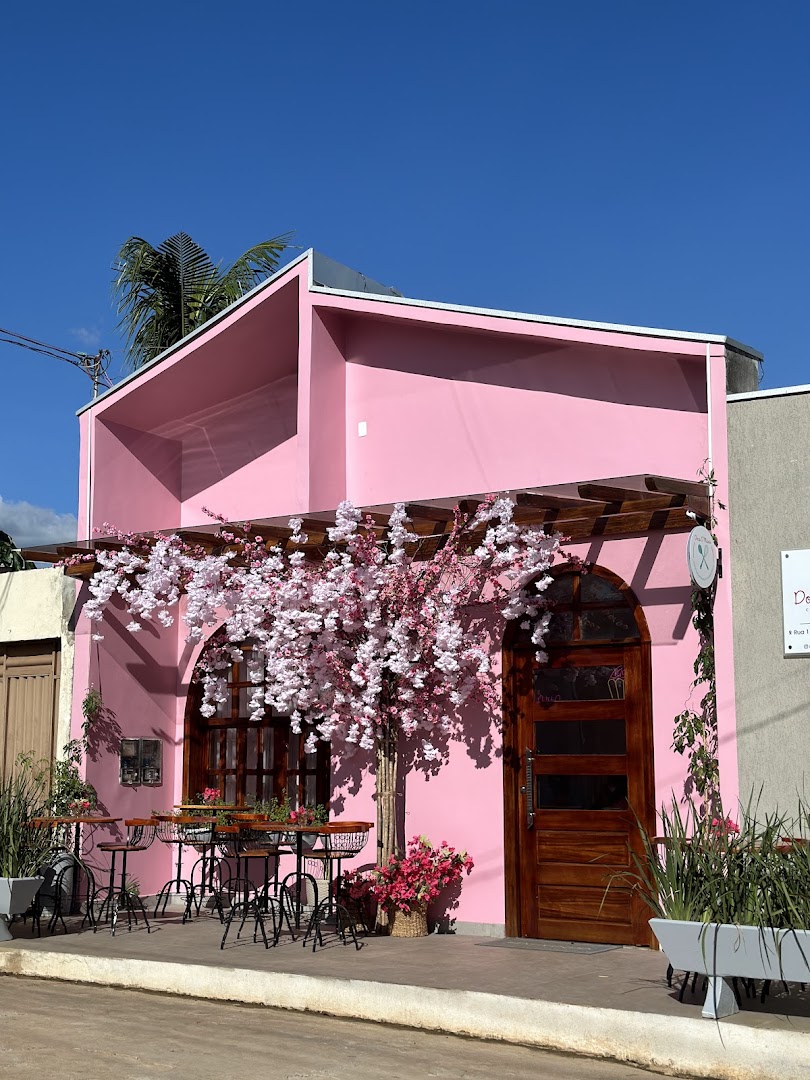 Fachada rosa da loja com uma cerejeira florida na frente