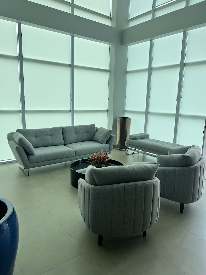Sala de espera com sofás cinza junto às janelas