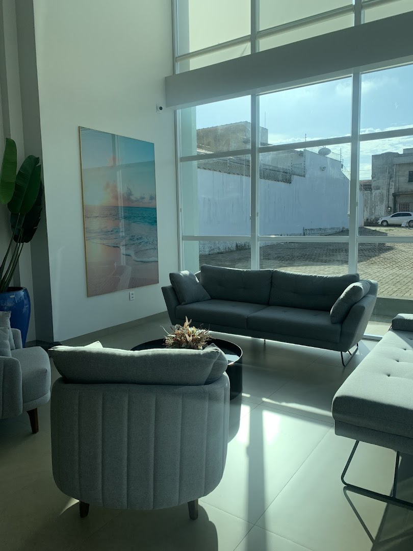 Sala de espera clara e ampla com sofá cinza