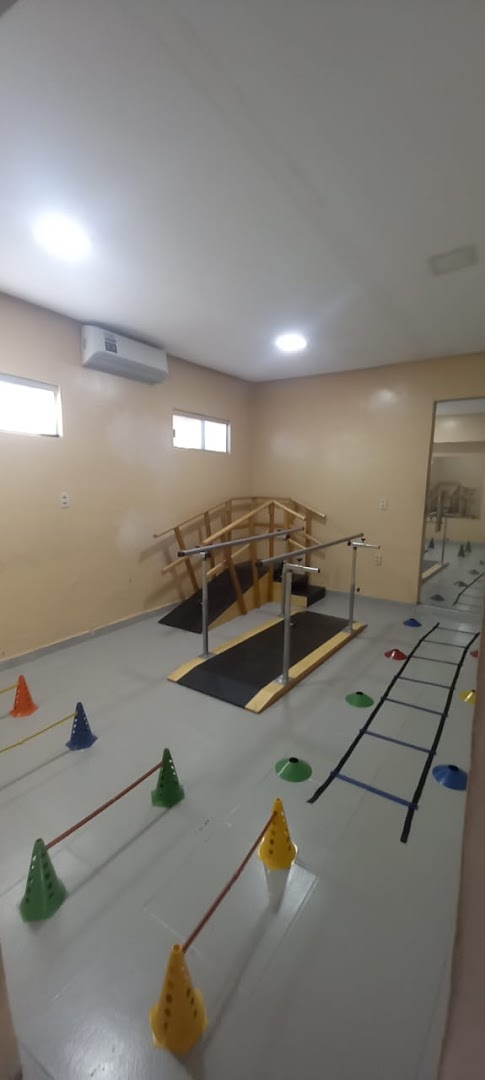 Sala de reabilitação da FA Fisio e Pilates com barras paralelas, rampa e circuito de cones coloridos