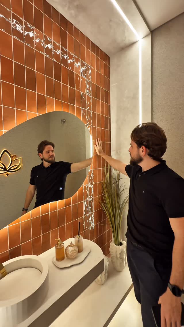 Lavabo com parede terracota, espelho orgânico e bancada planejada