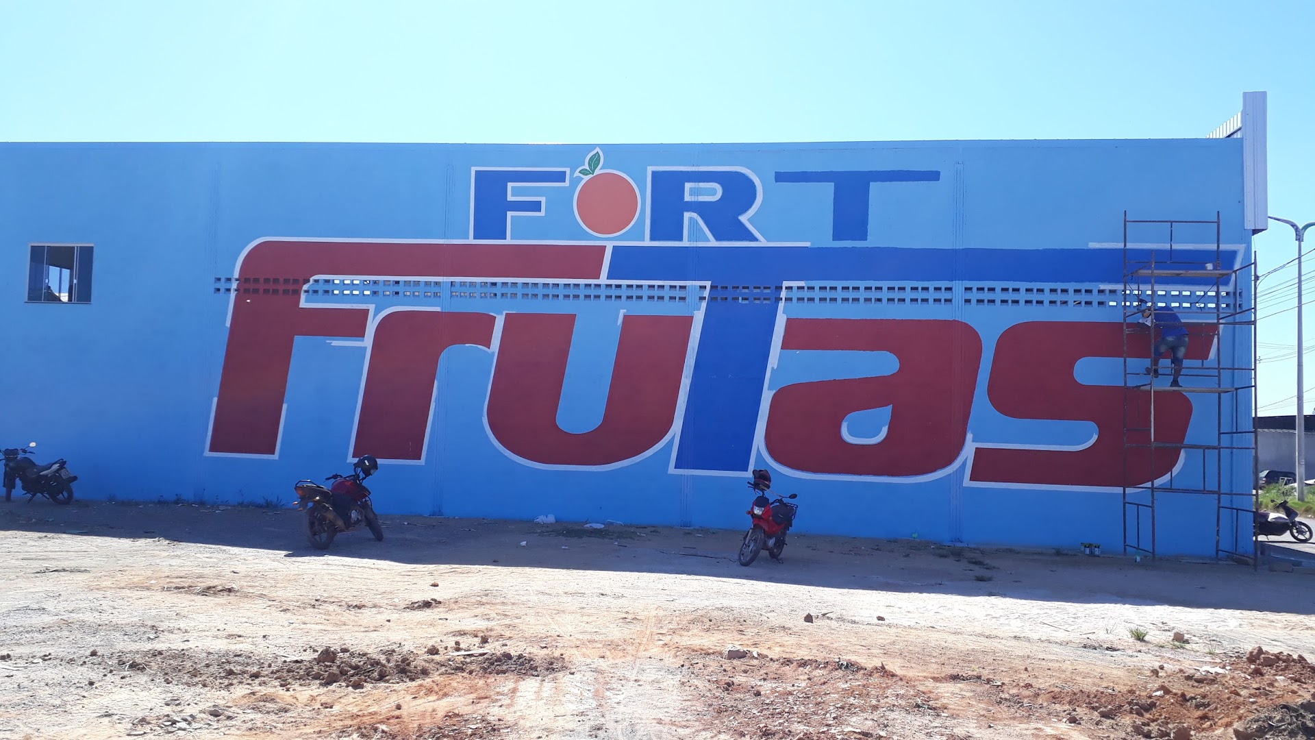 Parede do galpão pintada com o logo Fort Frutas