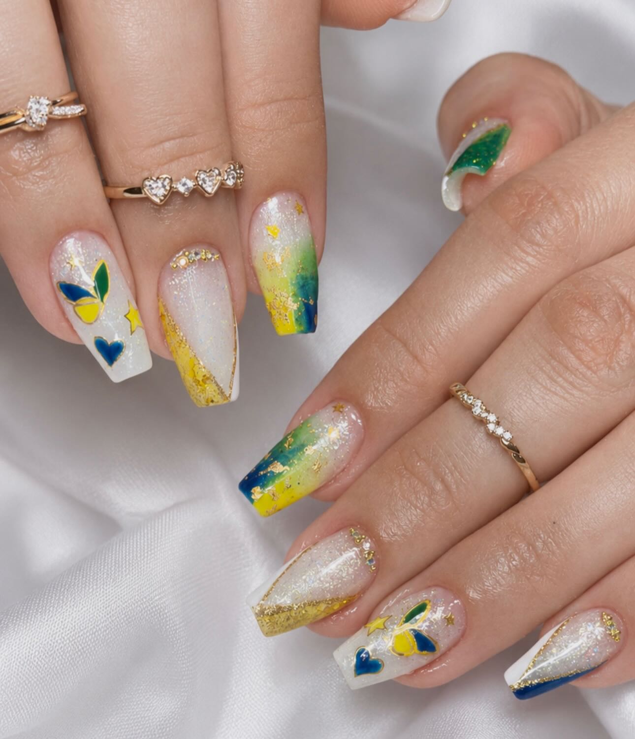 Nail art colorida com borboleta, flores e detalhes em dourado