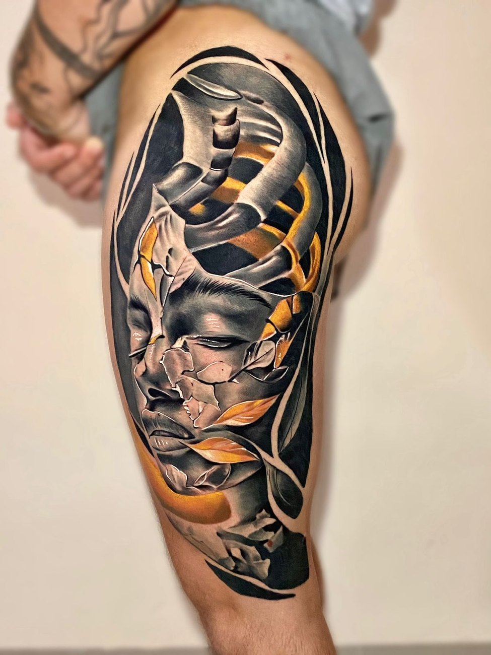 Tatuagem autoral de rosto com folhas e detalhes dourados