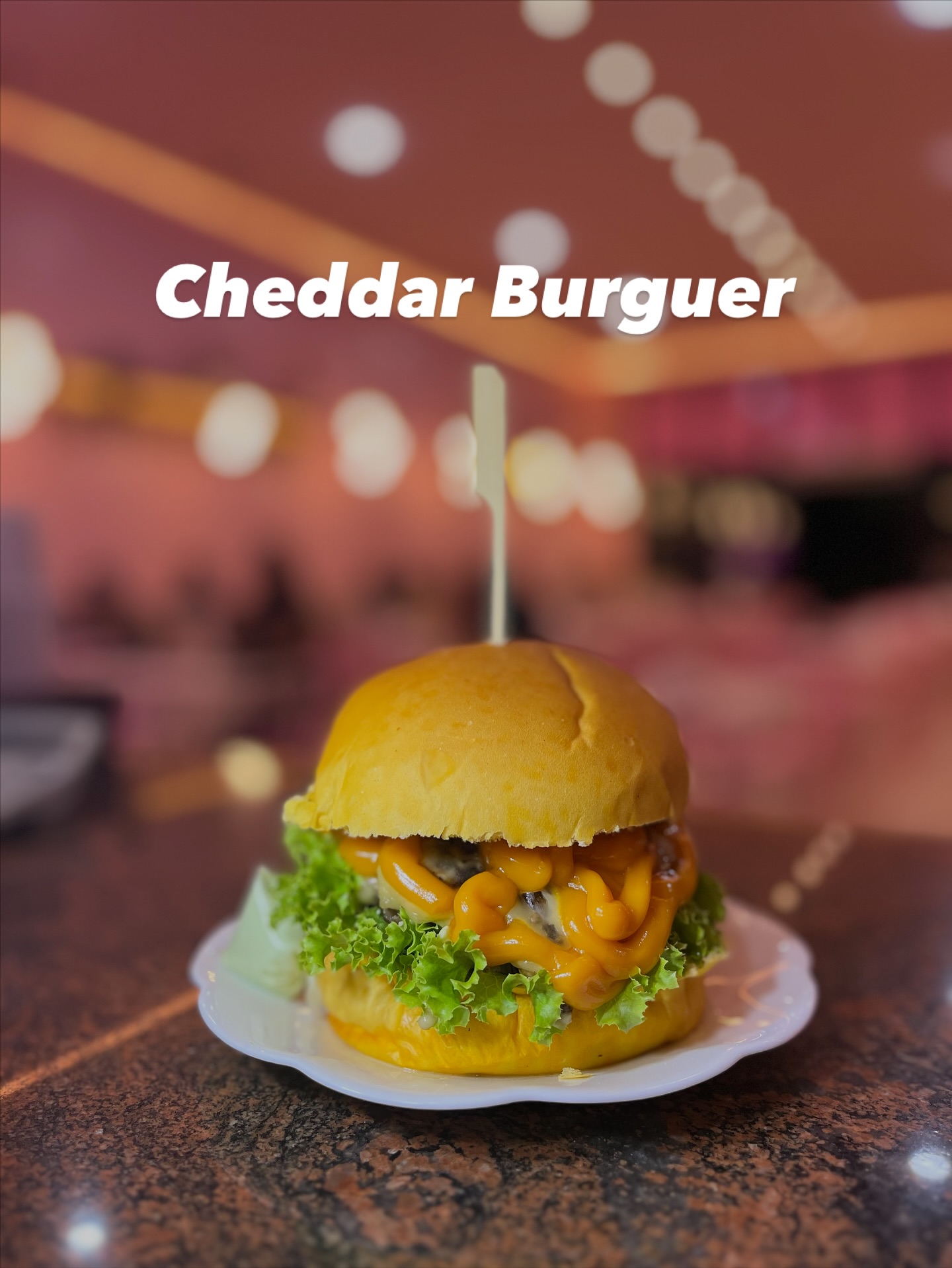 Cheddar burguer da Geerrê com luzes desfocadas ao fundo