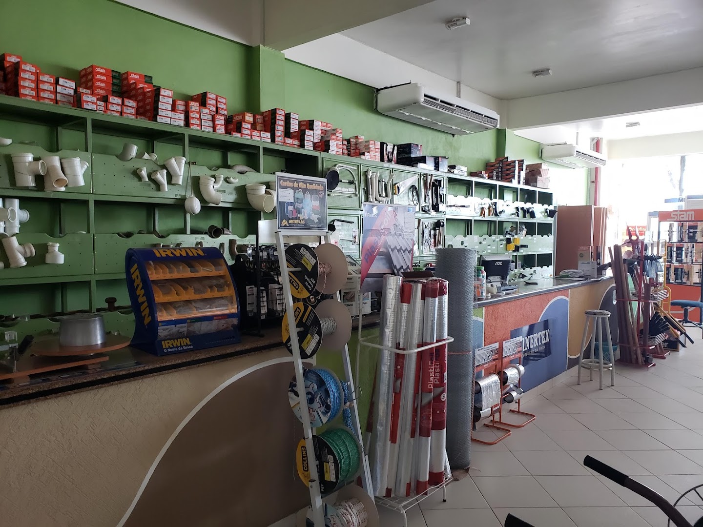 Interior da loja Guinhazi com balcão e prateleiras de ferragem e material de construção