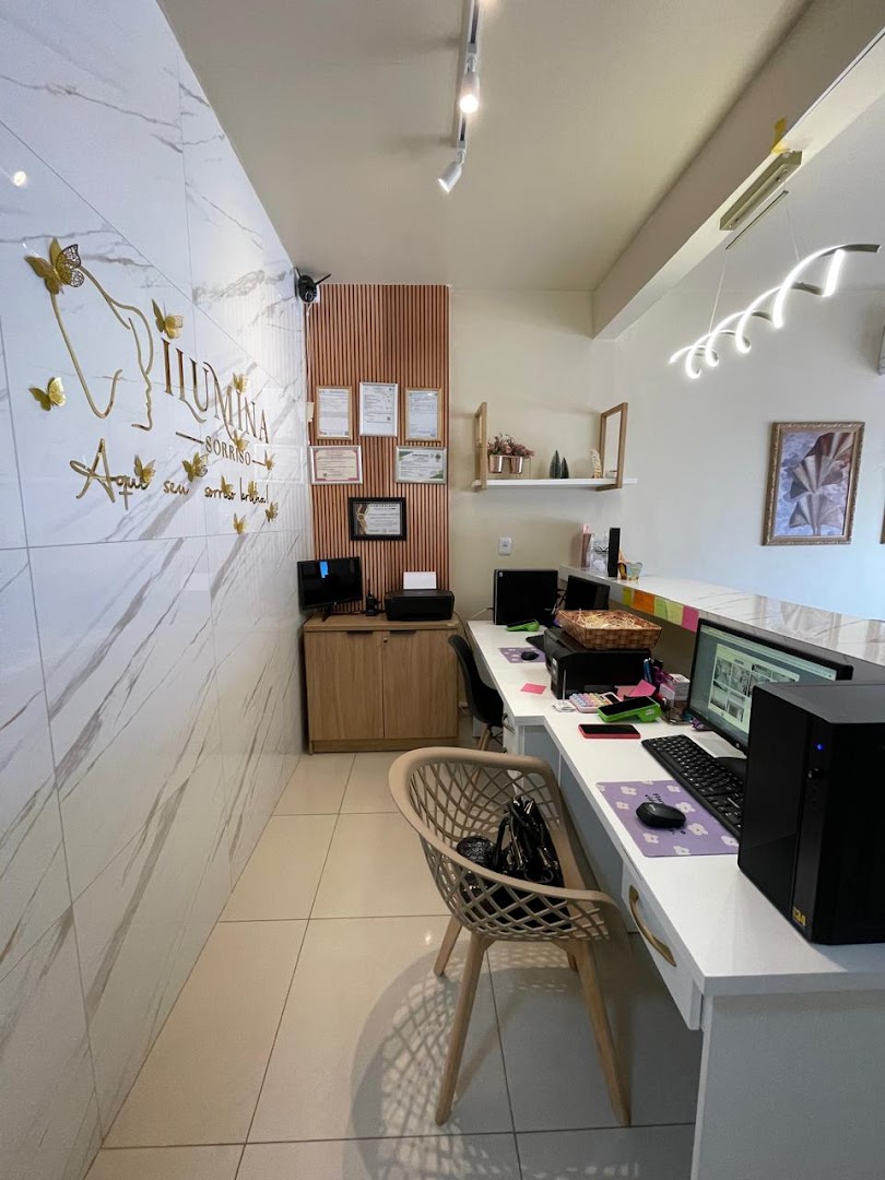 Recepção da clínica Ilúmina Sorriso, com parede de mármore e detalhes em dourado