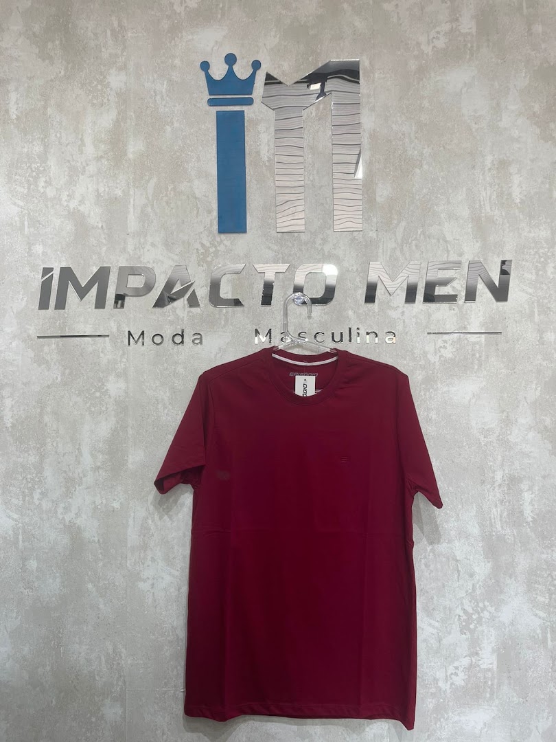 Camiseta da linha própria Impacto Men pendurada sobre parede de cimento queimado