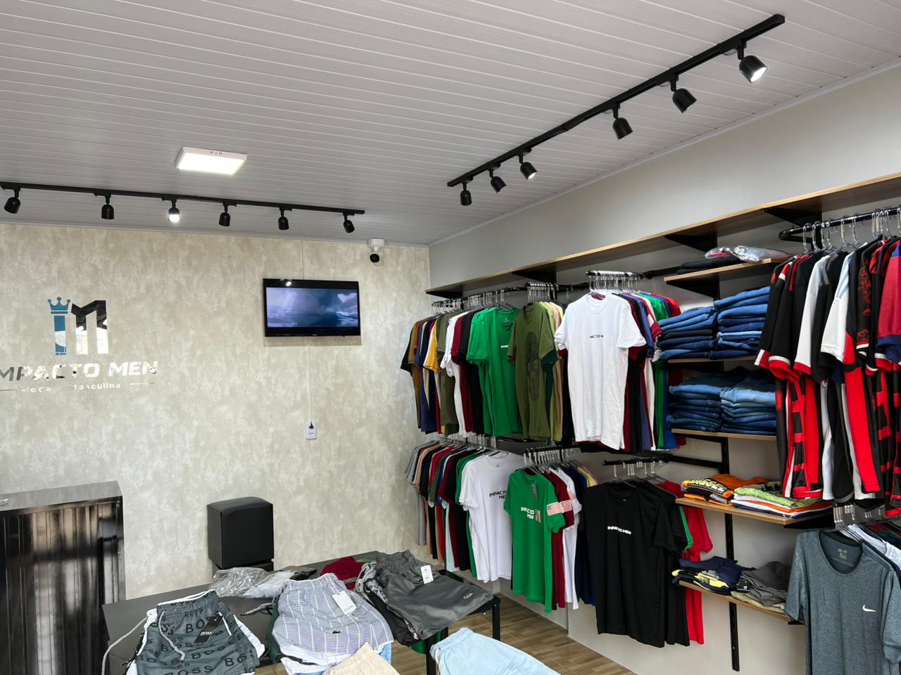 Interior da loja Impacto Men com araras de camisetas