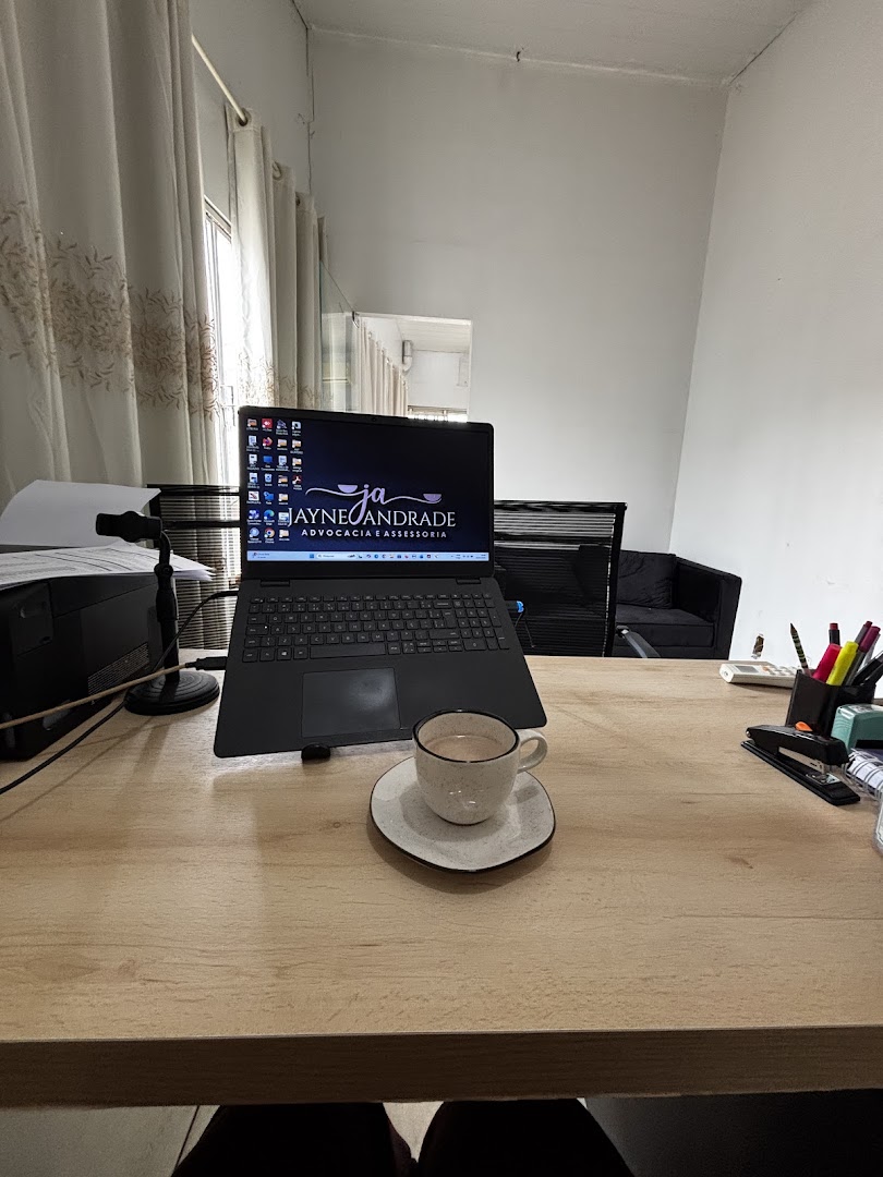 Mesa de trabalho no escritório, com notebook e um cafezinho