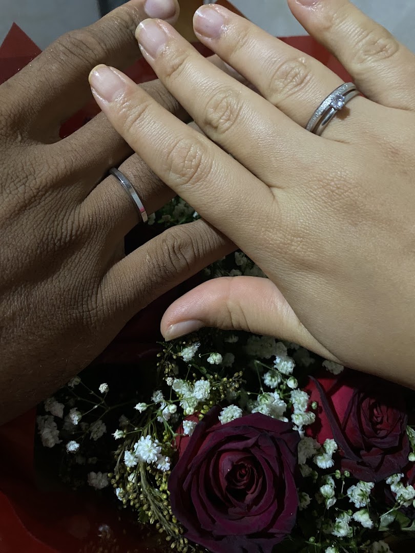 Alianças de casamento nas mãos do casal com rosas