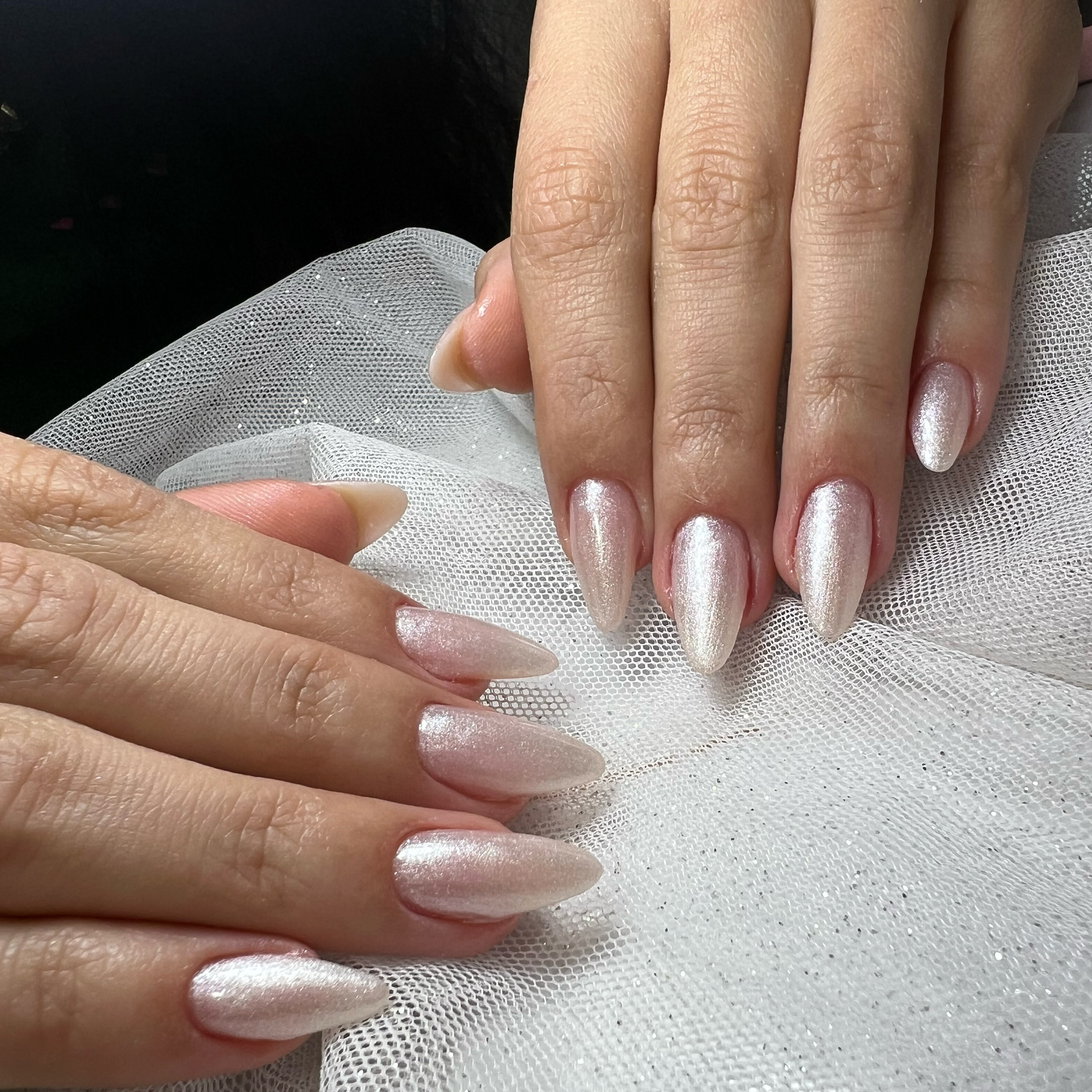 Unhas amendoadas com efeito pérola sobre tule branco