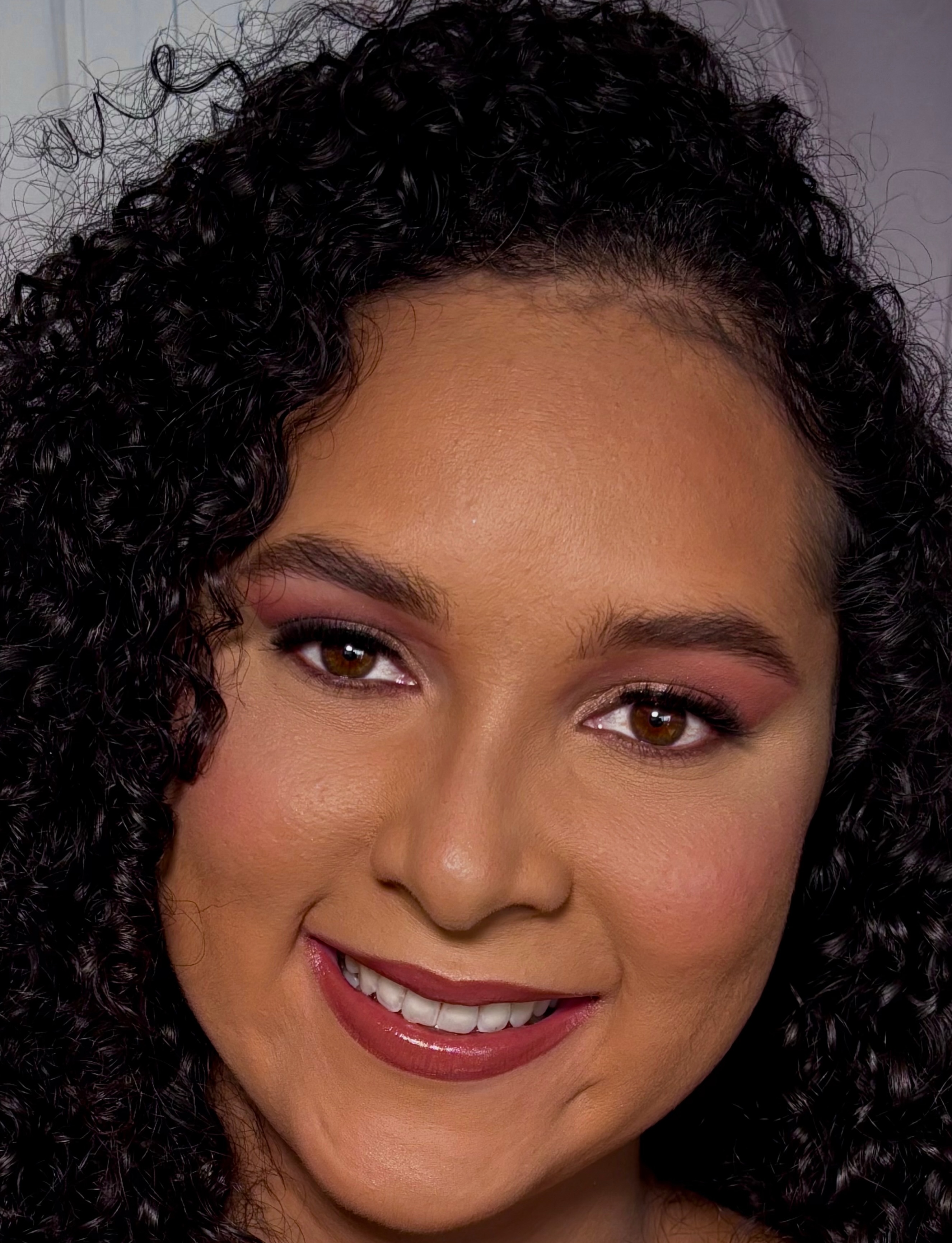 Cliente com maquiagem natural glam e cabelo cacheado
