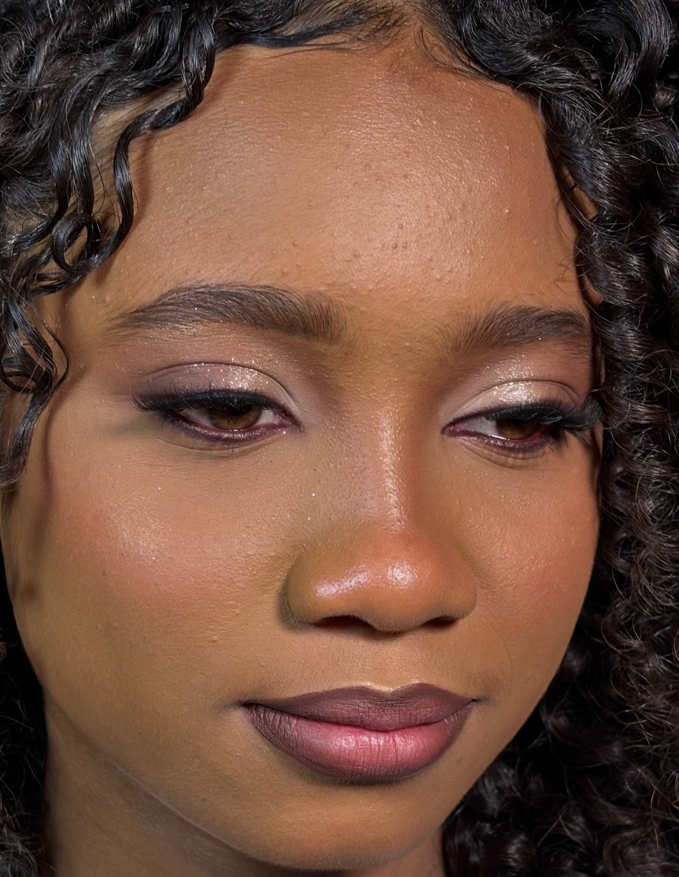 Cliente com maquiagem glam e brilho dourado nos olhos