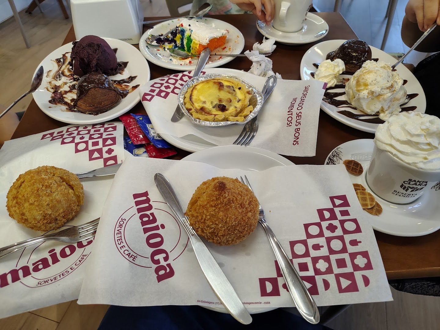 Mesa com doces, café e guardanapos da Maioca