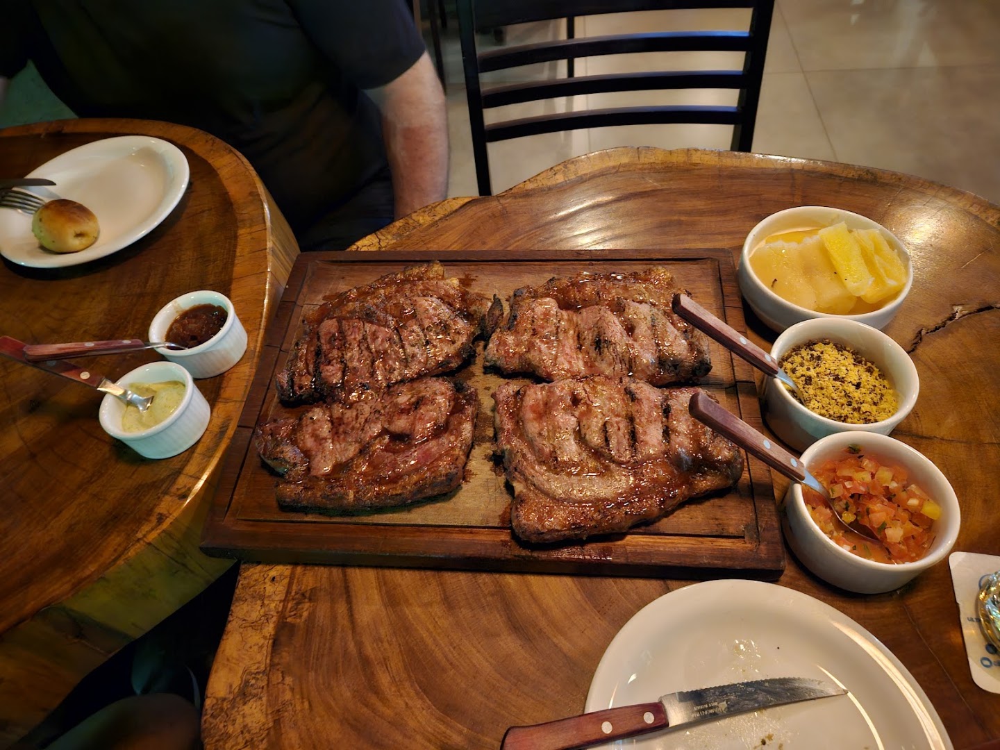 Cortes de carne grelhados servidos numa tábua com acompanhamentos