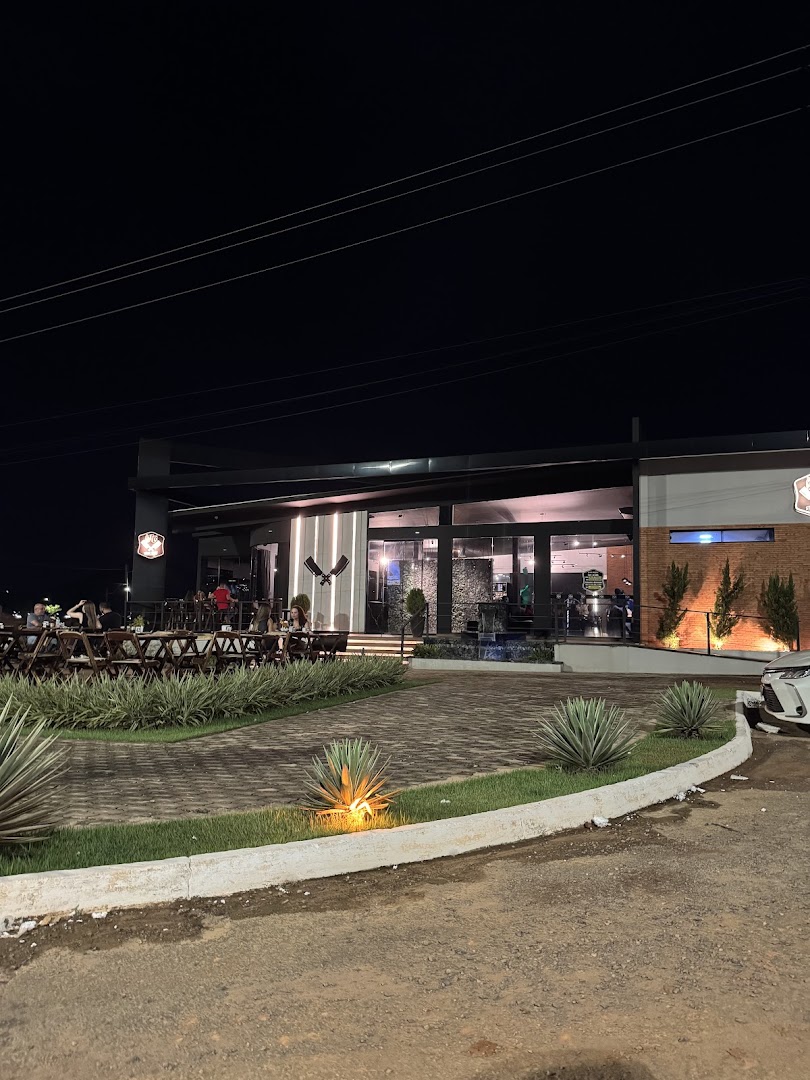 Fachada da casa à noite, iluminada, com uma fogueira acesa na frente
